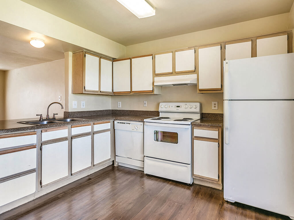 A light kitchen with hardwood floors at Paradise Oak Apartments in Austin, Texas.
